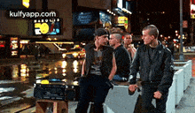 a group of young men are standing on a sidewalk next to a radio .