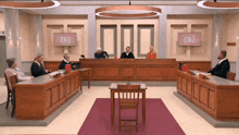 a group of judges are sitting in a courtroom with a sign that says [ s ] on it