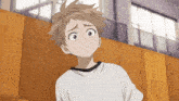 a boy with a sad look on his face is standing in front of a wooden wall