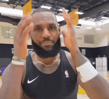 a man with a beard is wearing a black nike tank top and a gold chain necklace .