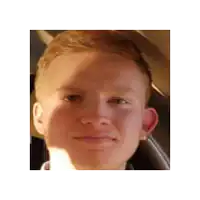 a close up of a young man 's face in a car looking at the camera .