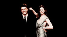 a man in a suit and tie is standing next to a woman in a dress dancing .