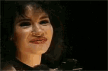a woman with a big smile on her face is making a funny face and waving her hand .