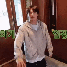 a man is standing in front of a door wearing a hoodie and a white shirt .