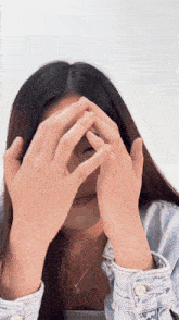 a woman covering her face with her hands while wearing a necklace