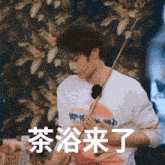 a man in a white shirt is holding a pool cue with chinese writing behind him