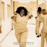 a woman is dancing in a hallway with a group of women .