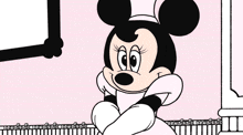a cartoon drawing of minnie mouse sitting on a ledge