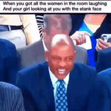 a man in a suit and tie is laughing while sitting in a crowd .