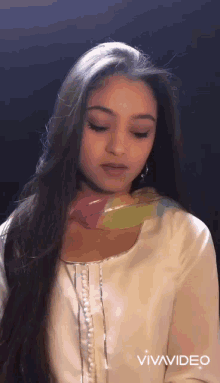 a woman with long hair is wearing a white dress and a scarf around her neck .