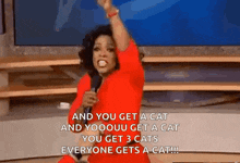 a woman in a red dress is holding a microphone and saying and you get a cat and everyone gets a cat .