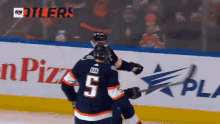 a hockey player with the number 5 on his jersey is hugging another player
