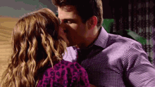 a man in a purple shirt kisses a woman in a purple shirt
