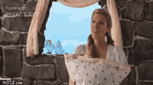 a woman is holding a pillow in front of a window with a picture of two birds on it