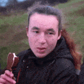 a man with a ponytail is eating an ice cream cone .
