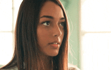 a close up of a young woman 's face with long hair looking at the camera .