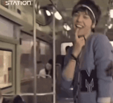 a man wearing a headband and a sweater with the letter m on it is standing on a train .