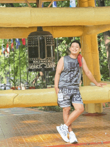 a man stands in front of a large bell that says world peace bell on it