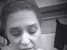 a black and white photo of a woman 's face with her eyes closed .