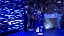 a man wearing a mask and a maar jersey stands on a stage