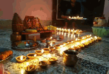 a man is holding a tray of candles in front of a statue