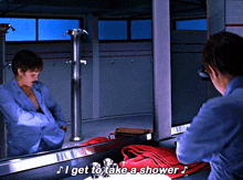 a woman in a blue suit is looking at herself in a mirror and says i get to take a shower
