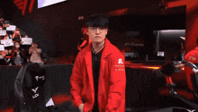 a man in a red jacket is standing in front of a chair that says lck on it .