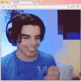a young man wearing headphones and a blue shirt is smiling and making a fist .