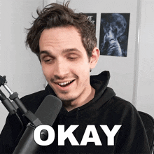 a man sitting in front of a microphone with okay written on the bottom