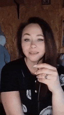 a woman wearing a black shirt and a ring is holding a microphone .