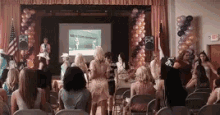 a group of women are sitting in front of a stage with balloons