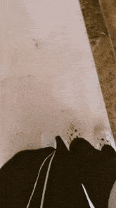 a person wearing black pants and white crocs is standing on a marble floor .