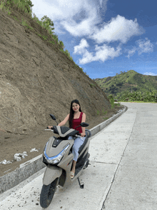 a woman is sitting on a yamaha scooter on a road