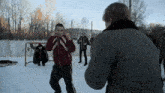 a group of men are boxing in the snow and one of them is wearing a red and white jacket