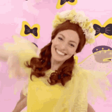 a woman wearing a yellow dress and a flower crown smiles