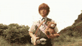 a man holding a teddy bear and a sash that says " a "