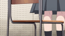 a girl in a skirt sits at a desk in front of a polka dot wall