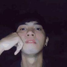 a close up of a young man 's face with his hand on his chin