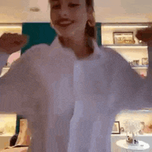 a woman in a white shirt is dancing with her arms outstretched .