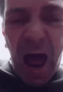 a close up of a man 's face with his mouth open and his eyes closed .