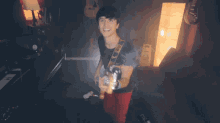 a man playing a guitar in a dark room with a yellow sign that says " caution "