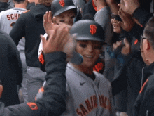 a baseball player wearing a san francisco giants uniform is being congratulated by his teammates