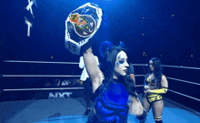 a woman in a wrestling ring holds up a belt that says ' nxt ' on it