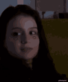 a close up of a woman 's face with two hearts drawn on her face