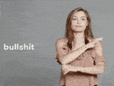 a woman in a pink top is making a bullshit sign