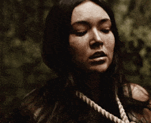 a woman with a rope around her neck looks at the camera .