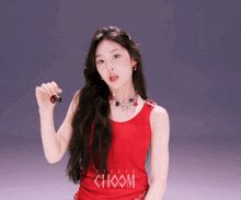 a woman in a red choom tank top holds a cherry