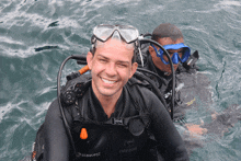 a man wearing a seaquest wetsuit smiles while swimming