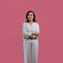 a woman in a white shirt and white pants is standing with her arms outstretched