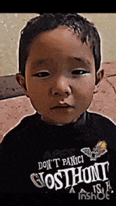 a young boy wearing a black shirt that says ghost hunt